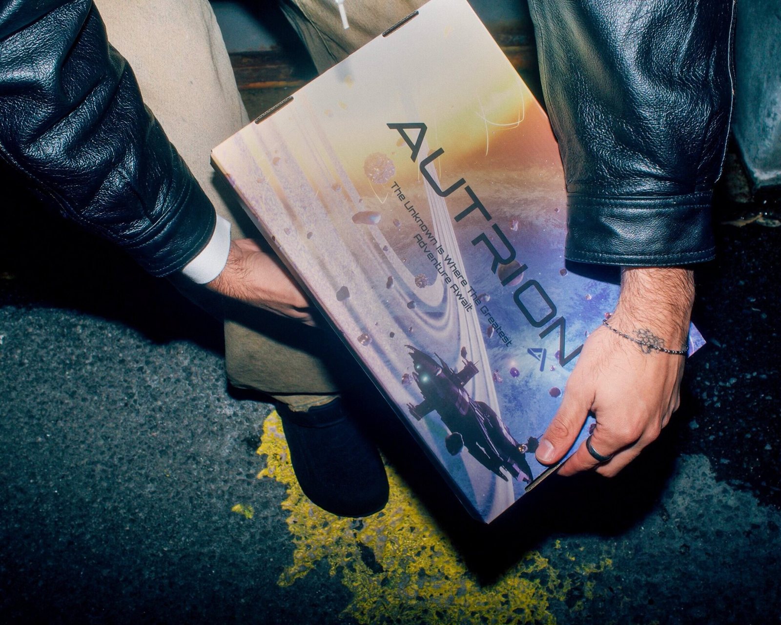 Hands holding the printed Autrion shoe box at night.