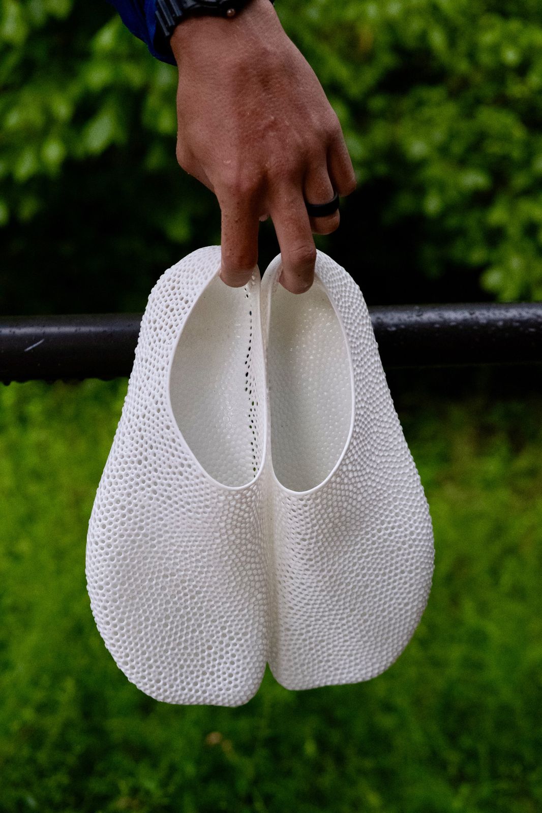 A hand holding a pair of white printed lattice slip-ons.