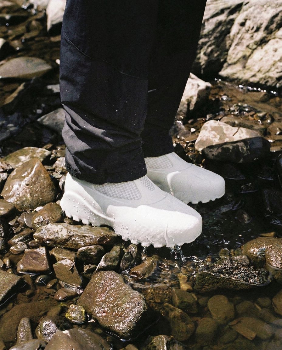 White printed Autrion shoes standing in a shallow, rocky stream.